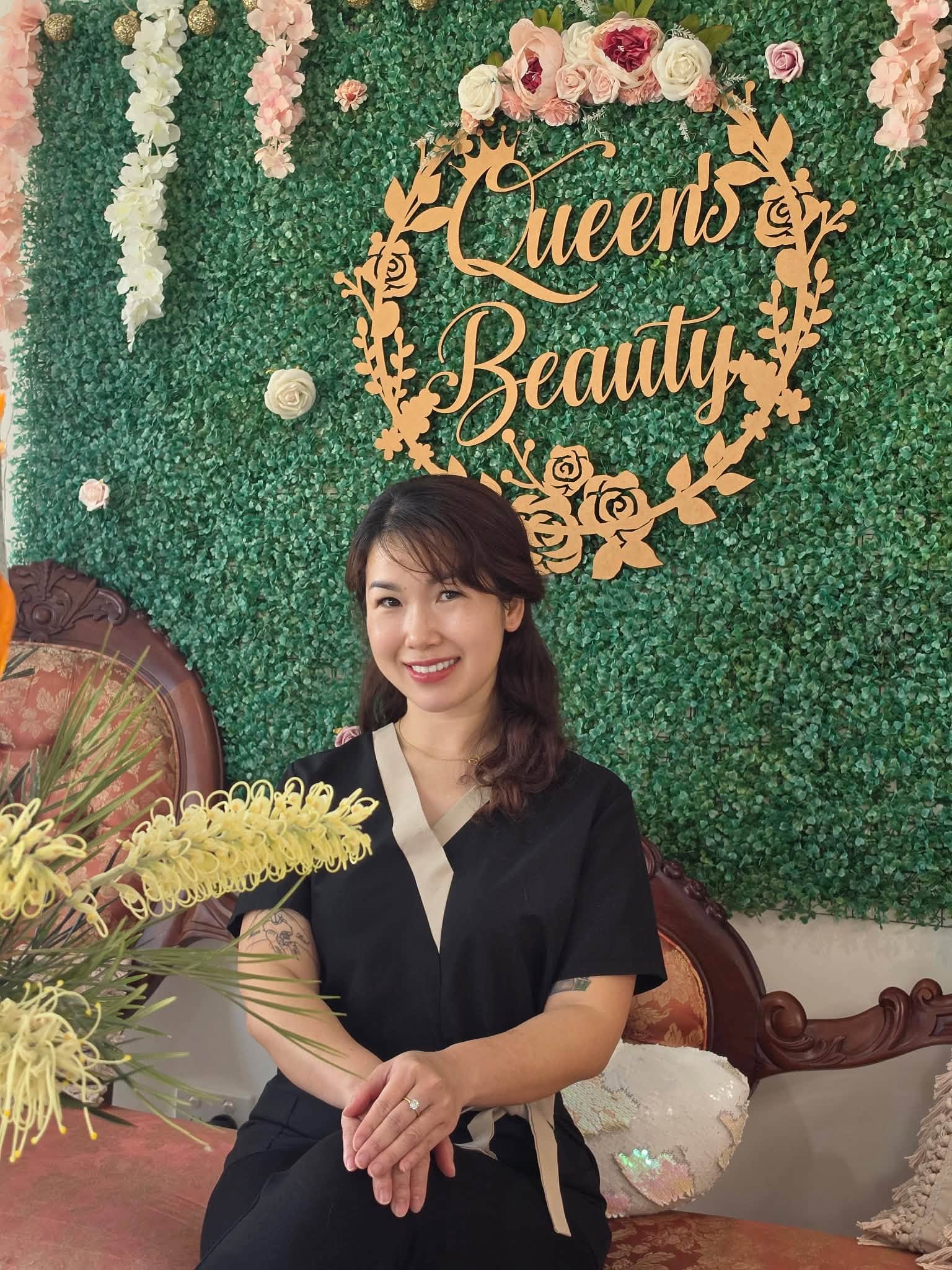 Quinnie, lash master and trainer, in front of the Queen's Beauty sign
